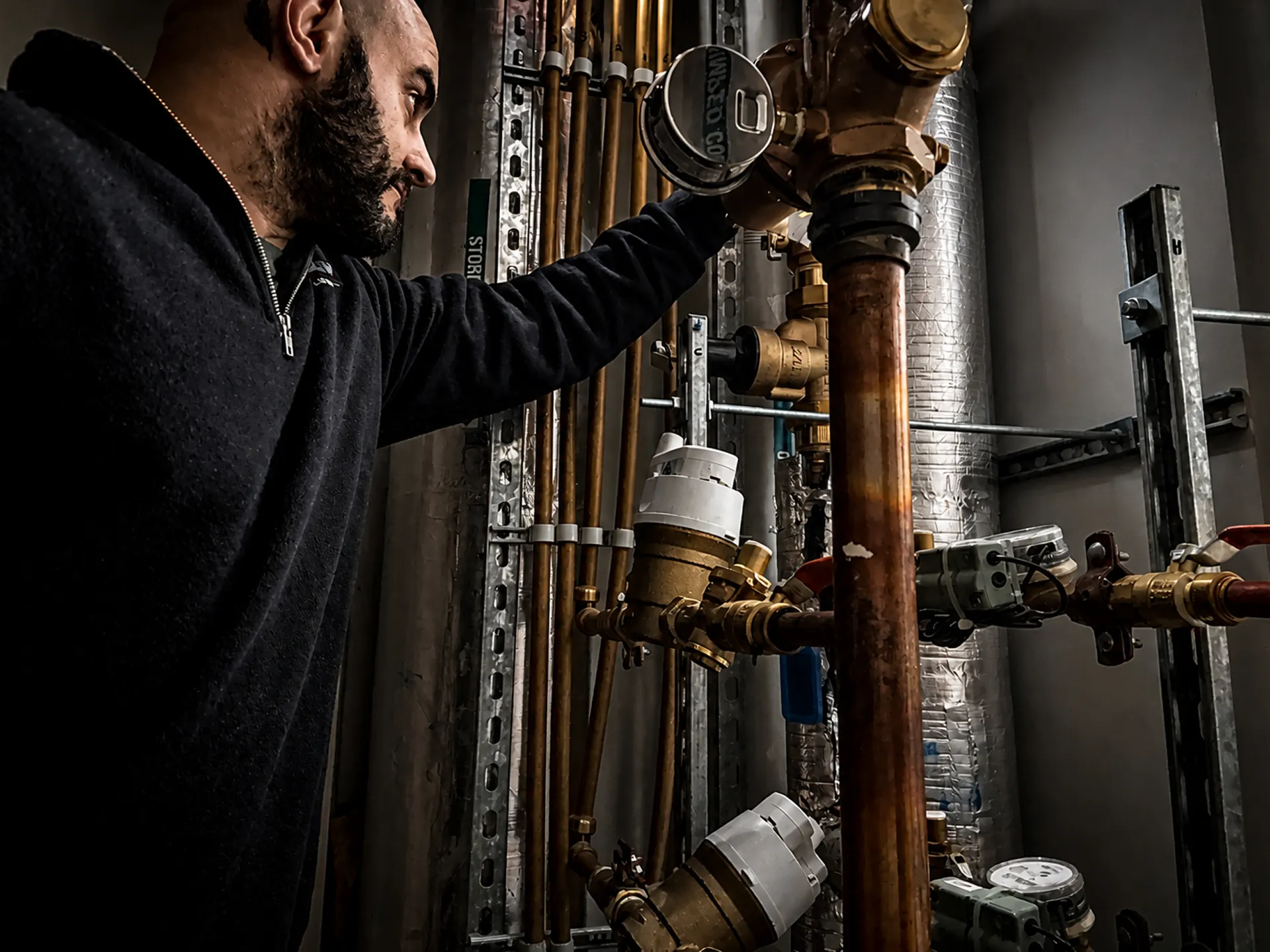 Controlled Flow Plumbing technician inspecting hydraulic pipework and quality-checking a commercial installation