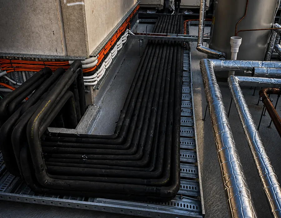Insulated pipework and cable runs installed in a commercial plant room, documented as part of an asset condition report
