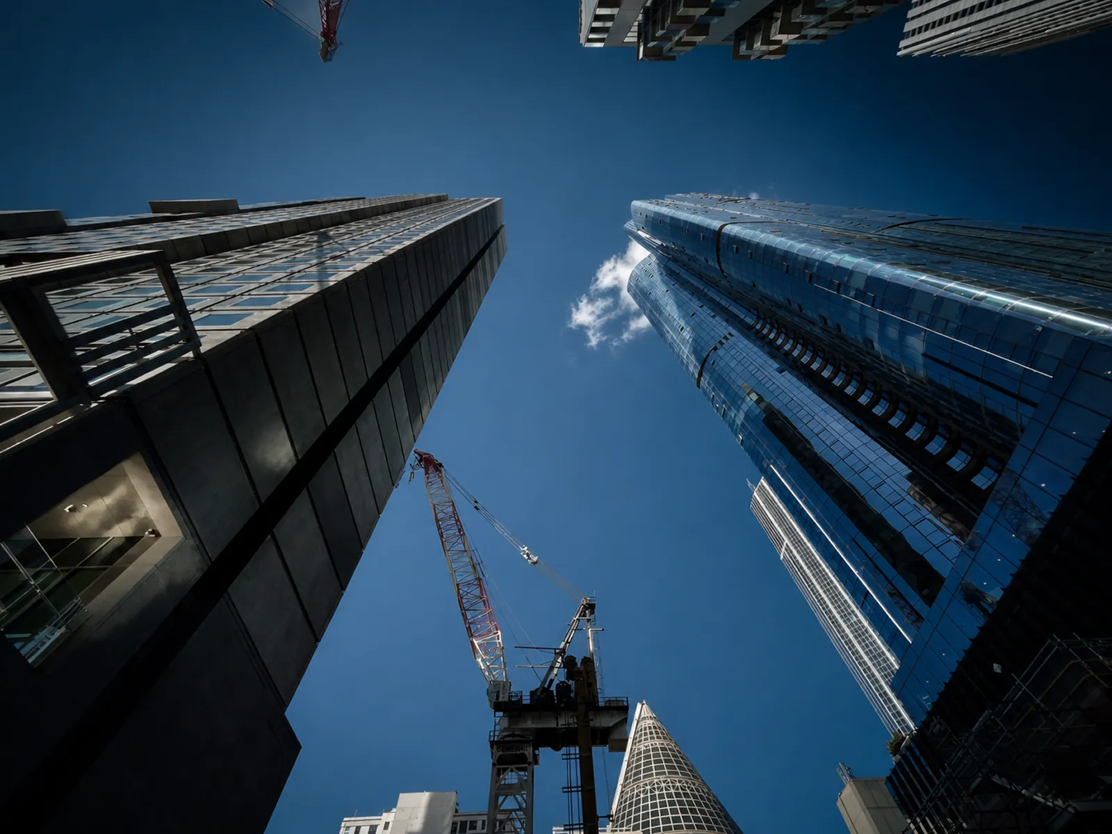 Looking up at Melbourne commercial high-rise towers and a construction crane against a clear sky