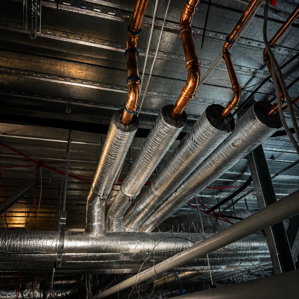 Insulated copper water pipework routed through a commercial plant room ceiling