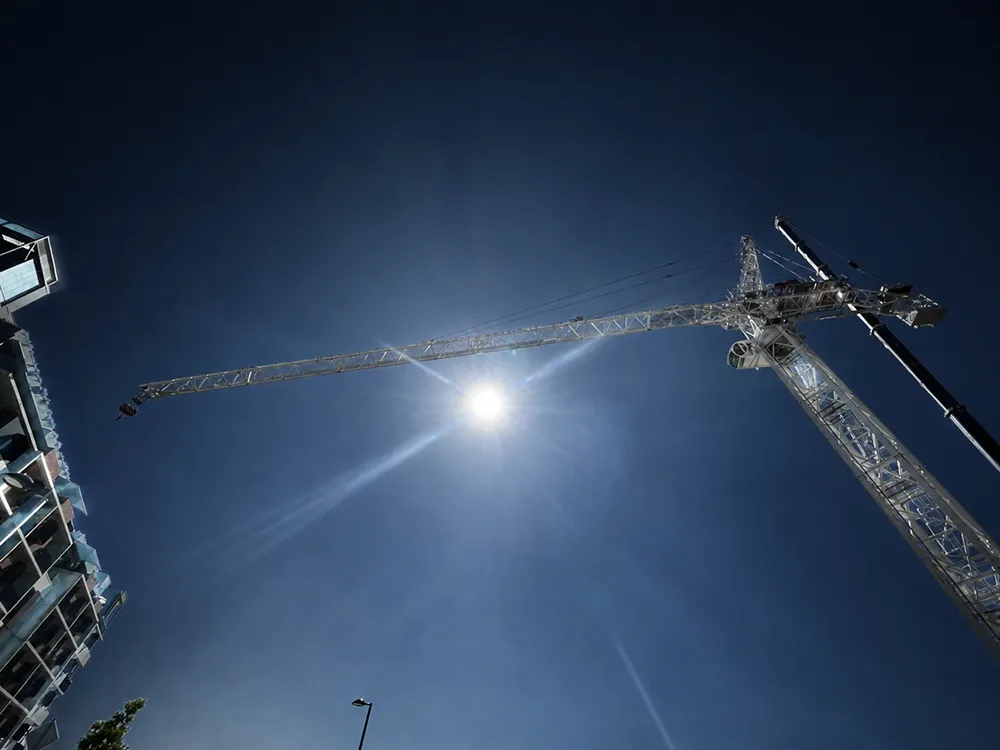 Crane against a bright blue sky on a commercial building site during an office-to-apartment conversion
