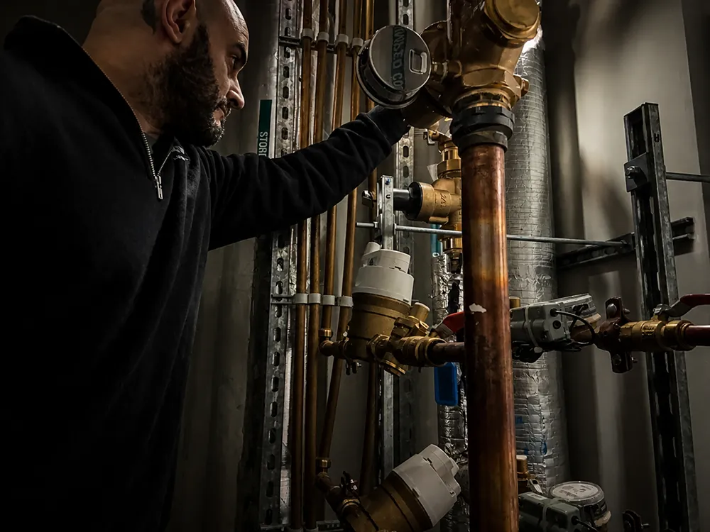 Controlled Flow Plumbing technician inspecting a copper hydraulic assembly as part of testing and commissioning